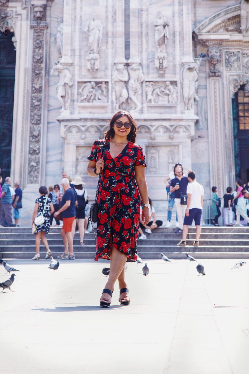 Fashion blogger outside of Duomo di Milano wearing a rose printed summer dress from Primark, black and brown wedges from Vince Camuto and a Rebecca Minkoff handbag.